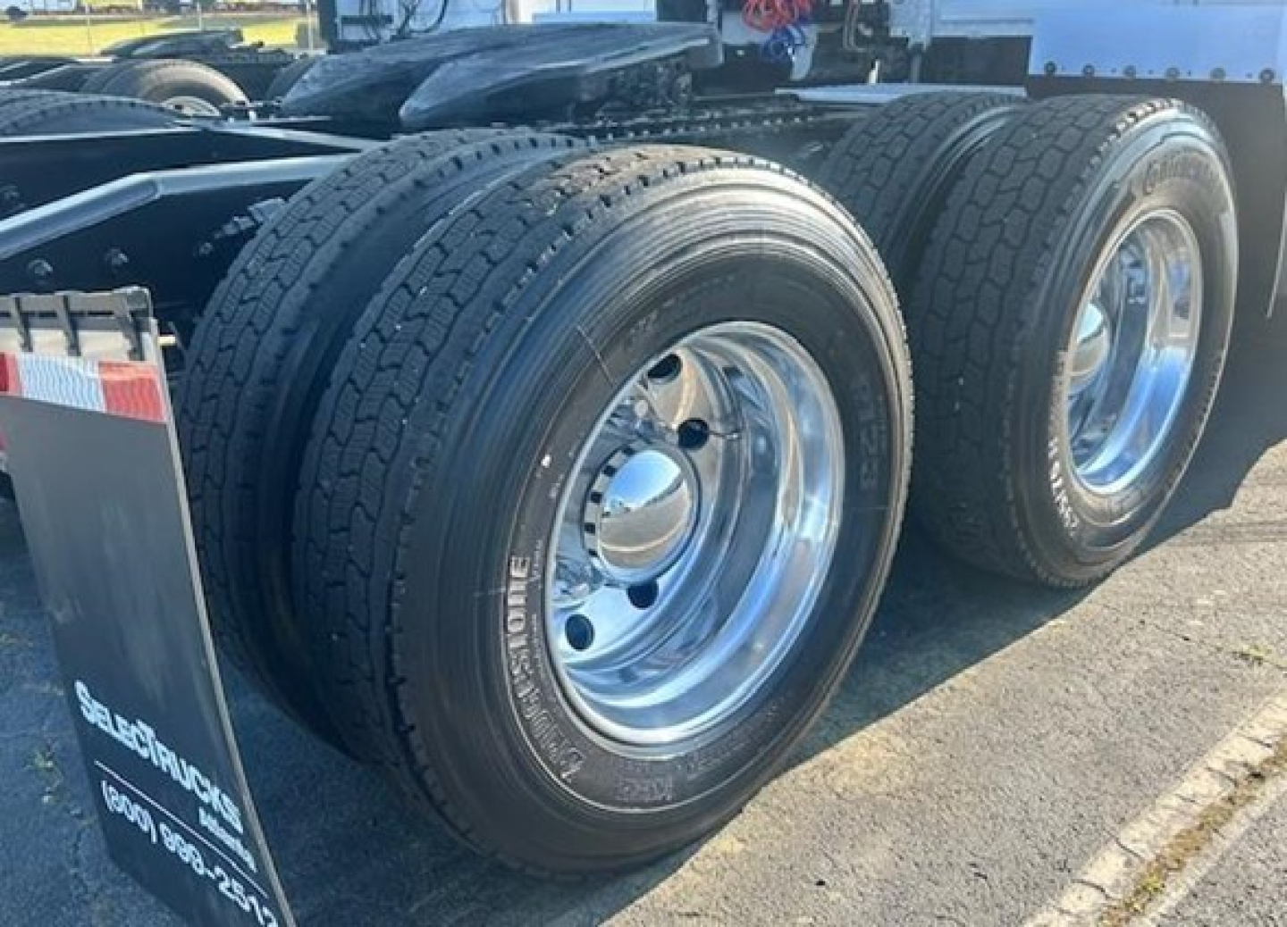 Truck wheel assembly showing dual rear aluminum rims with black tire treads and valve stems on a Freightliner Cascadia 126 chassis, viewed from the side.