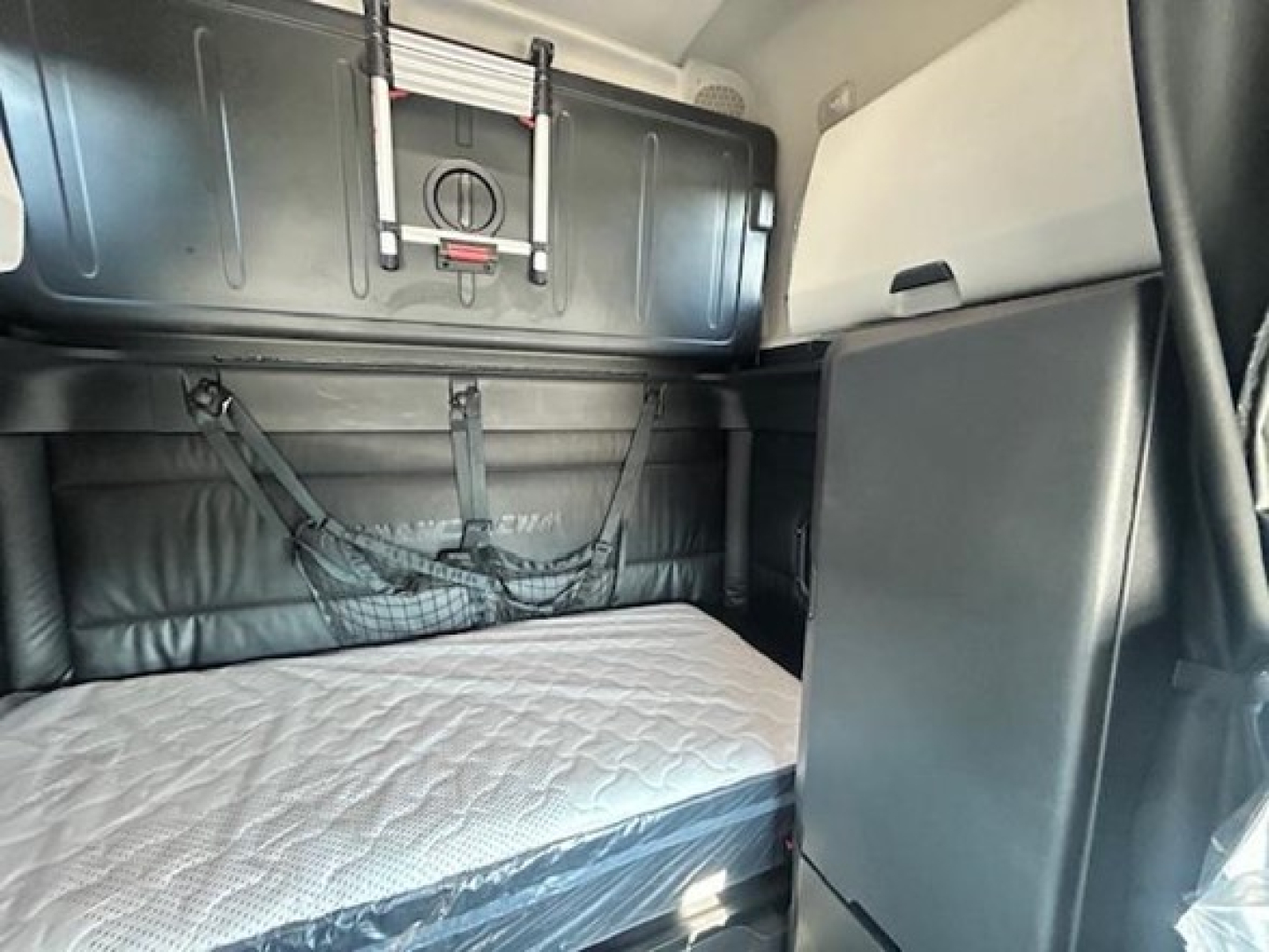 Freightliner Cascadia 126 sleeper cab interior with bunk bed mattress and storage cabinet.