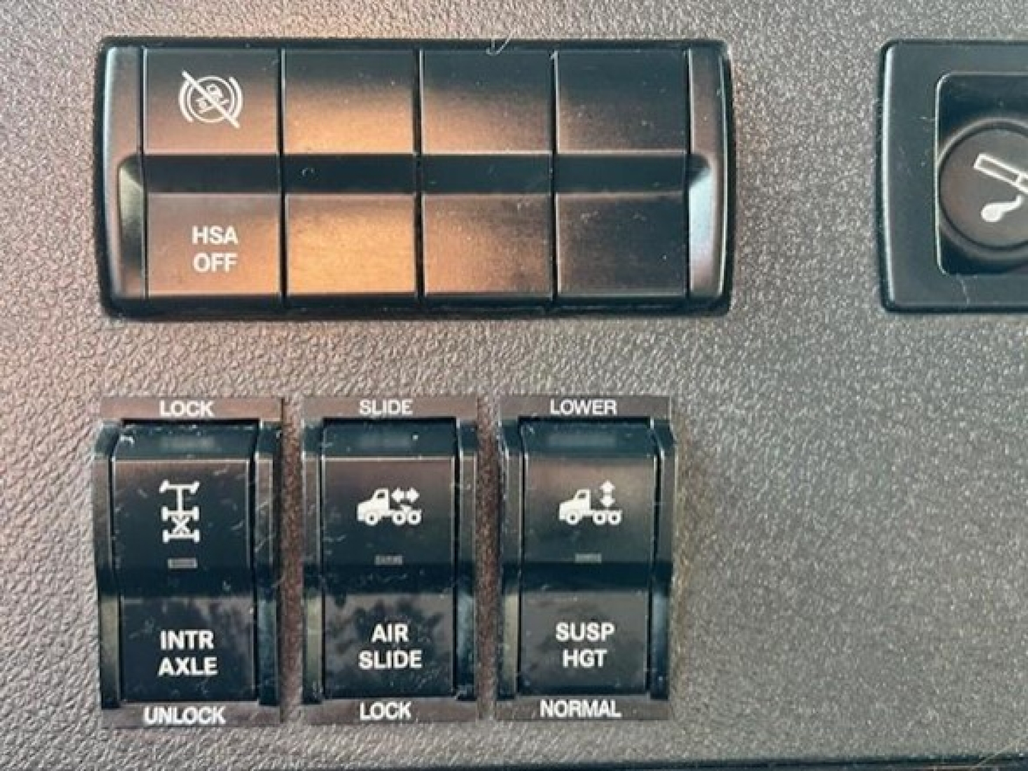 Dashboard controls showing HSA OFF switch and multiple locking/slide switches in Freightliner Cascadia cab.