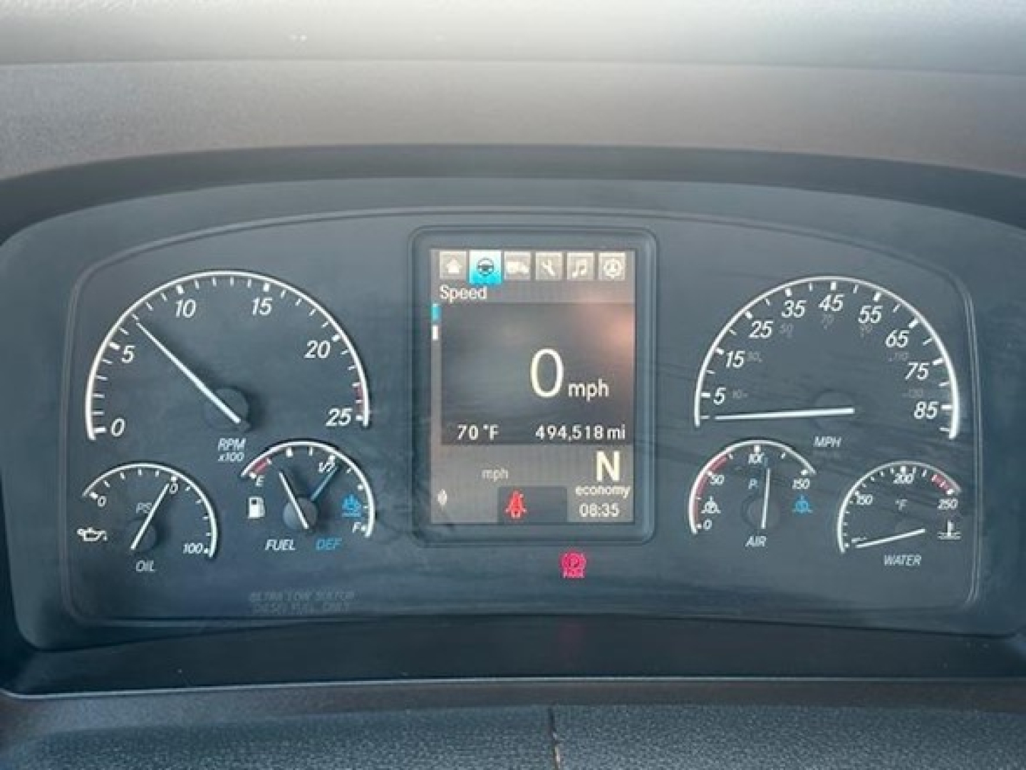Dashboard of a Freightliner Cascadia showing digital speedometer at 0 mph, and analog gauges for RPM, oil, fuel, coolant, air, and transmission with center display.