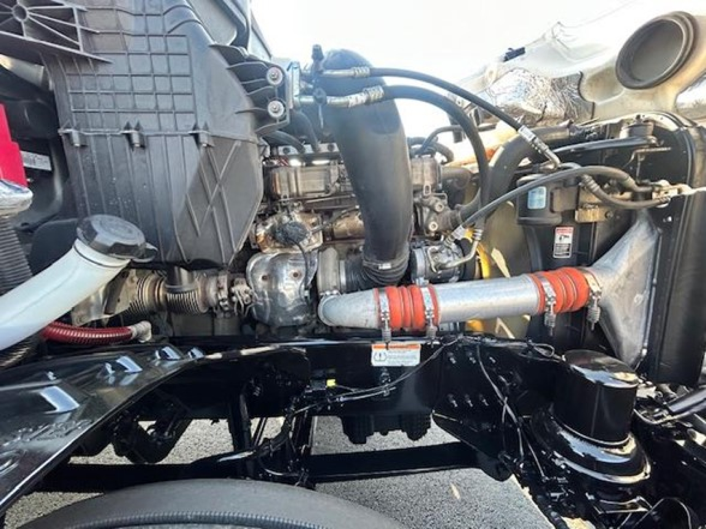 Engine bay of a Freightliner Cascadia showing intake, turbo piping, and coolant hoses with red-orange silicone couplers.