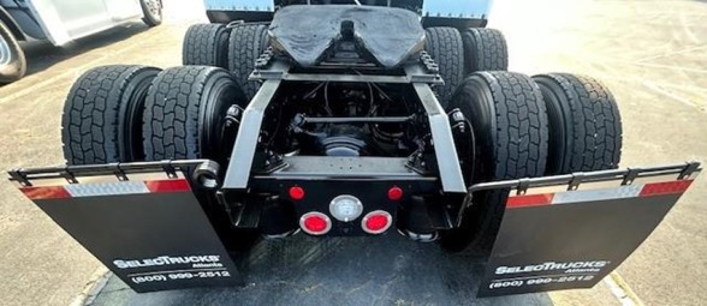 Rear view of a Freightliner Cascadia truck showing dual rear axles, fifth-wheel area, and mud flaps with text