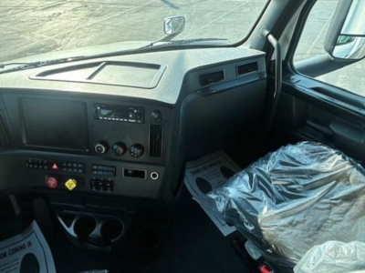 Truck cab interior of a 2023 Freightliner Cascadia 126 showing dashboard controls and passenger seat covered with plastic.