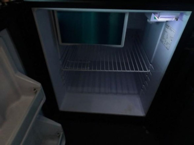 Fridge/freezer compartment inside a Freightliner Cascadia cab showing empty shelves and interior light.