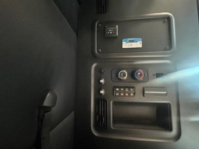 Cab interior panel of a Freightliner Cascadia showing a small blue-and-white label, control dials, and switch panel in view.