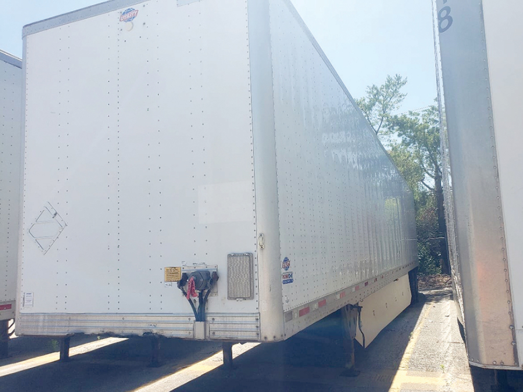 Trailer rear and side view of a white Utility 4000D-X trailer showing back doors and connector hardware.