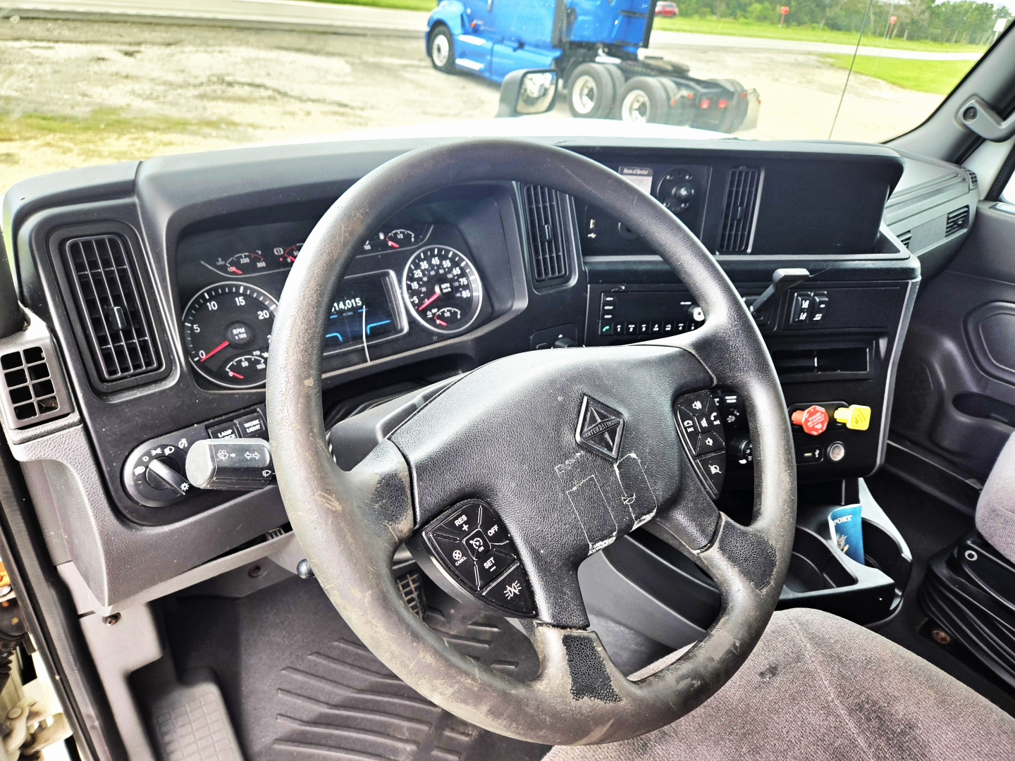 Truck cab interior showing steering wheel, dashboard gauges, and center console with gear shifter and controls in a 2020 International condo double bunk sleeper.