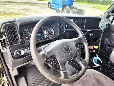 Truck cab interior showing steering wheel, dashboard gauges, and center console with gear shifter and controls in a 2020 International condo double bunk sleeper.