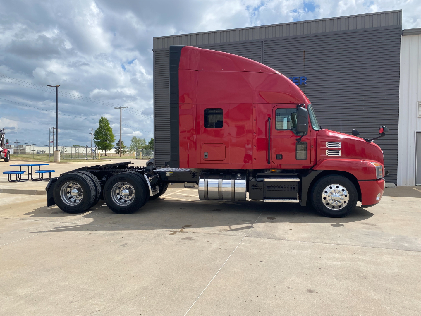 Truck side view showing red 2020 Mack AN64T70 sleeper tractor with three rear axles and fuel tanks.