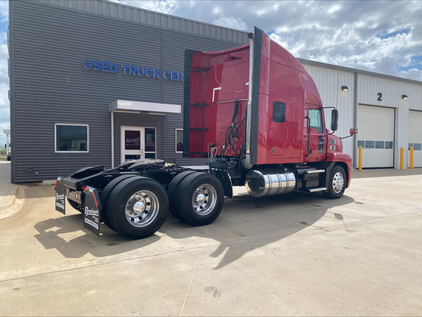 2020 Mack AN64T70 conventional sleeper truck in a dealership lot, side view showing red cab, fuel tanks, and dual rear axles.