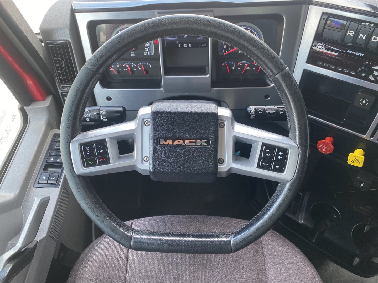 Mack AN64T70 truck steering wheel and dashboard view showing Mack badge and instrument cluster.