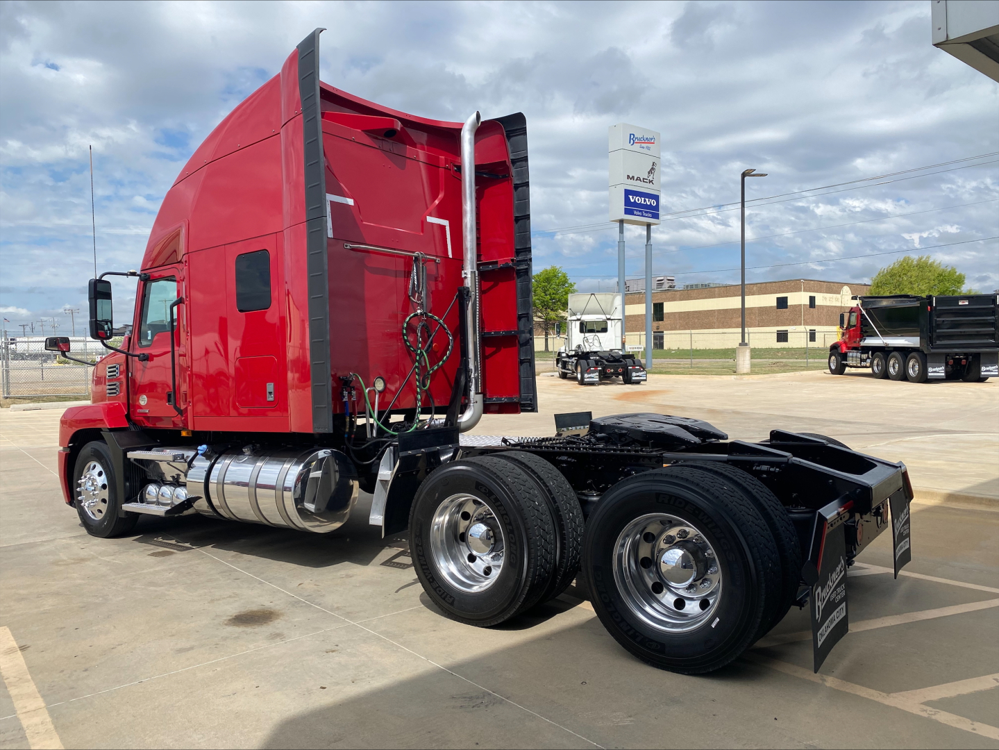 Mack AN64T70 tractor truck chassis with red sleeper cab and triple rear axles, fuel tanks, and exhaust pipes visible.