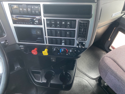 Dashboard area of a 2020 Mack AN64T70 showing gear selector, control panel, climate controls, and cup holders.
