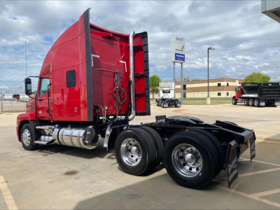 Mack AN64T70 tractor truck chassis with red sleeper cab and triple rear axles, fuel tanks, and exhaust pipes visible.