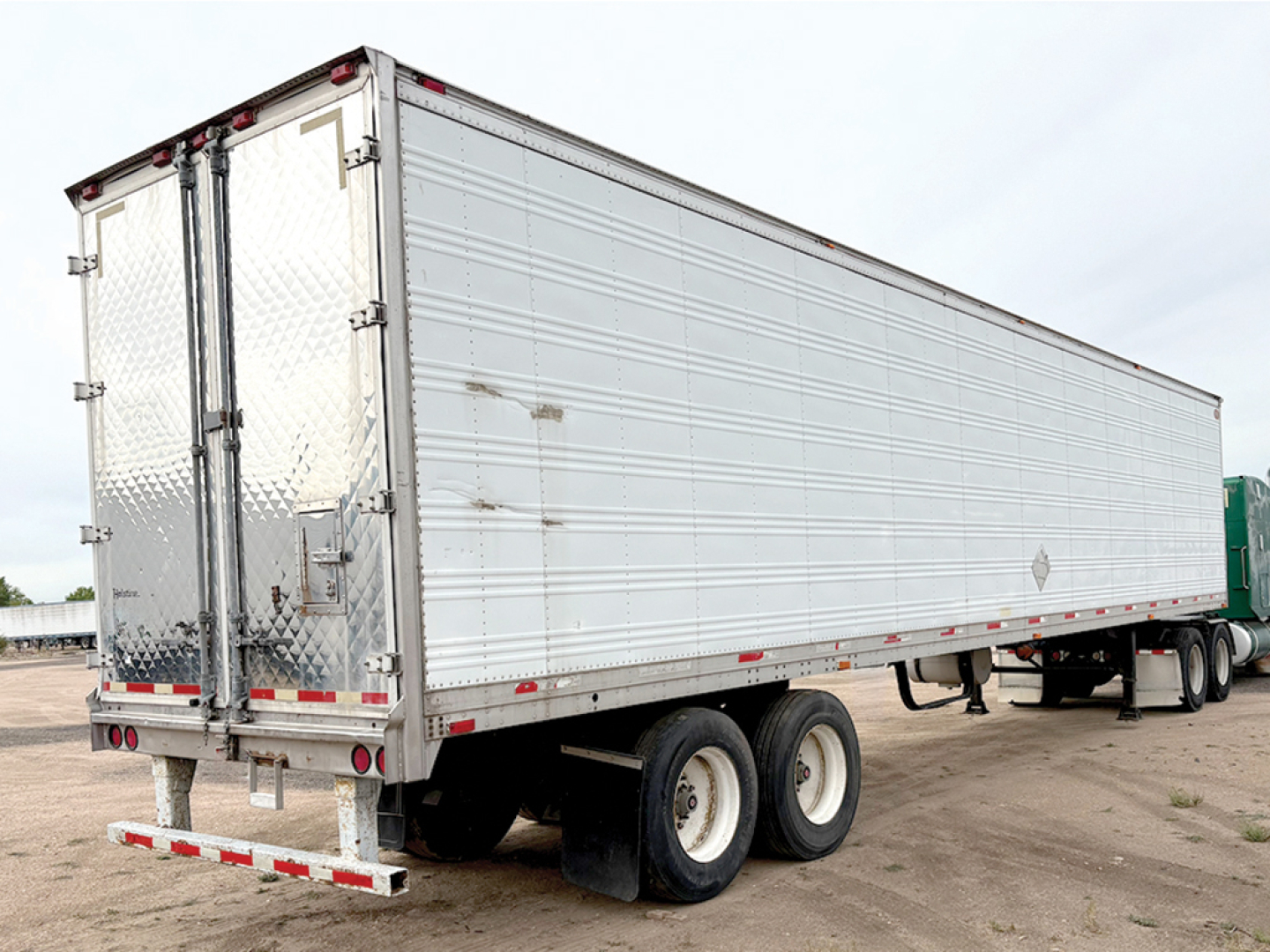 Aluminum reefer trailer showing rear doors and dual-axle tandem wheels.
