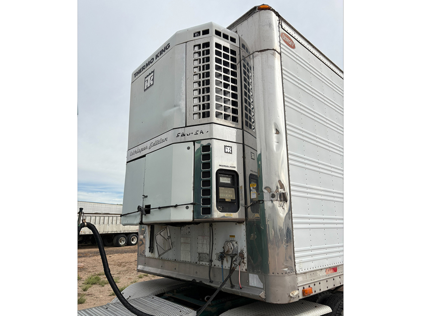 Reefer trailer front with cooling unit and aluminum body, FRS-3500 refrigeration system visible, side door closed.