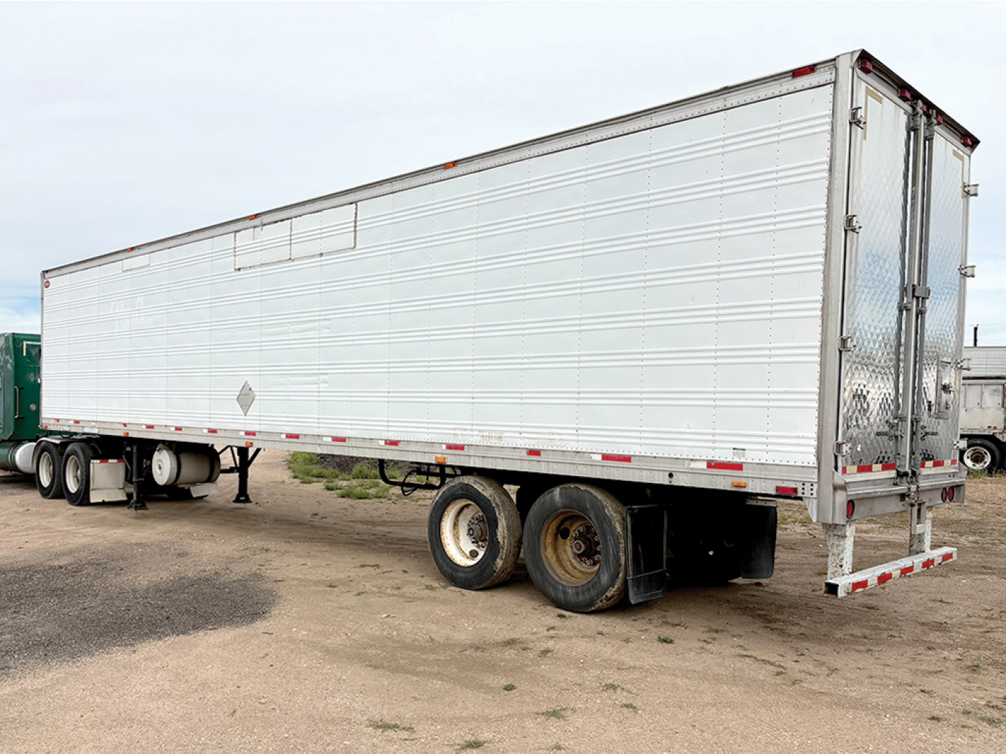 Aluminum reefer trailer side view showing dual rear doors and tandem axle set.