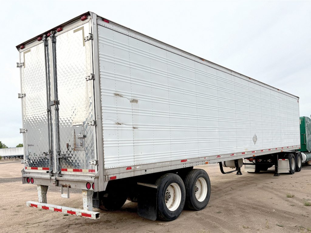 Aluminum reefer trailer showing rear doors and dual-axle tandem wheels.