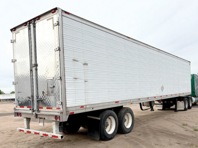 Aluminum reefer trailer showing rear doors and dual-axle tandem wheels.
