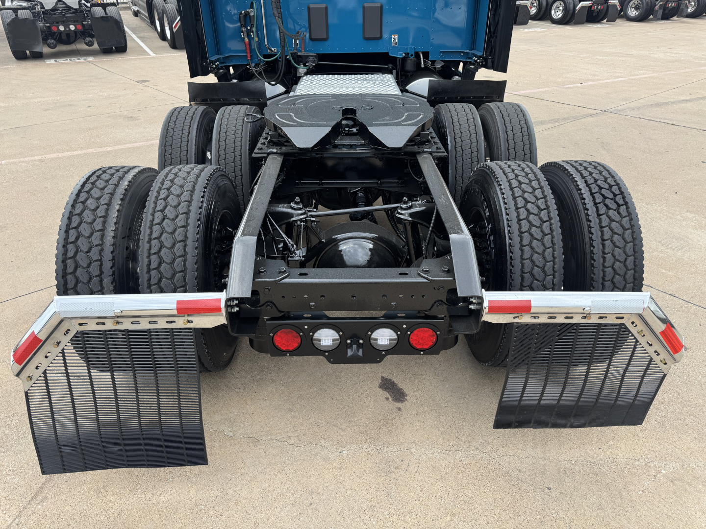 Kenworth T680 rear tractor view with dual rear axles and mudflaps, 6-wheel arrangement, fifth-wheel and hitch area visible, standard bumper reflectors.