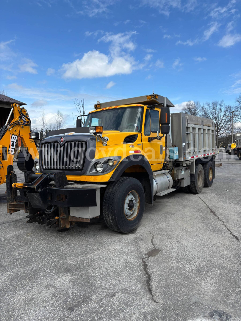 Dump truck showing 2011 International 7600 dump truck in yellow with black grille, front bumper guard, and dump bed; stock number 30360 visible.