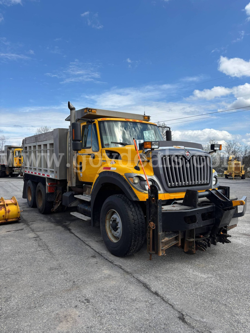 Dump truck with yellow cab and gray dump bed, front view in lot