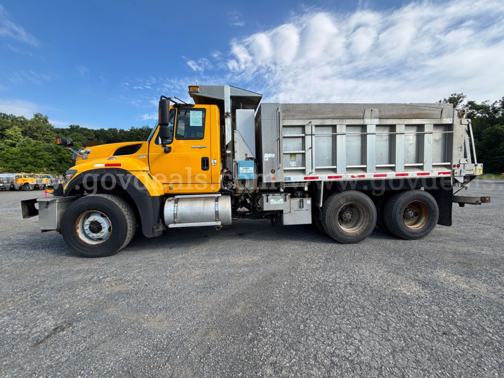 2011 International 7600 dump truck side view showing yellow cab and gray dump bed with dual rear axles.