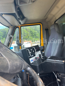 International 7600 dump truck interior cab view showing steering wheel, control joystick, dashboard with gauges, and yellow door frame.