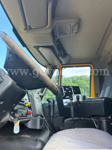 Cab interior of an International 7600 dump truck showing steering wheel, dash controls, and overhead console.