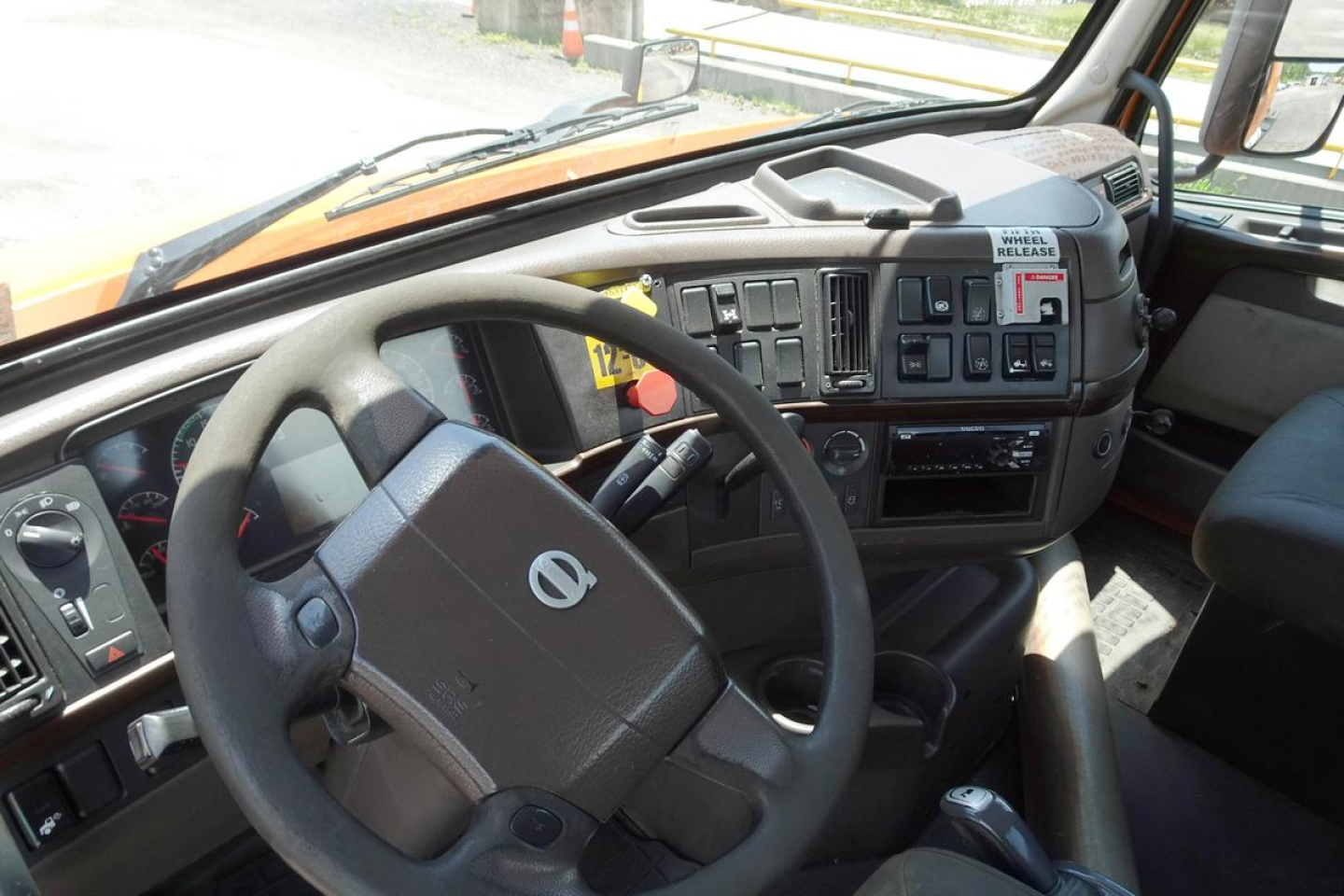 Volvo truck interior view showing steering wheel and dashboard with control panels and vents.