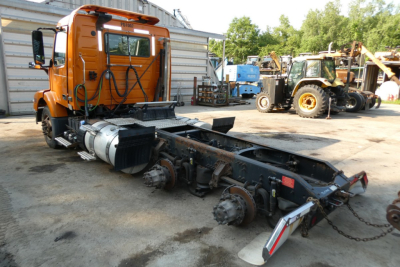 Volvo VNM64T chassis with cab detached showing drivetrain components and suspension undercarriage.