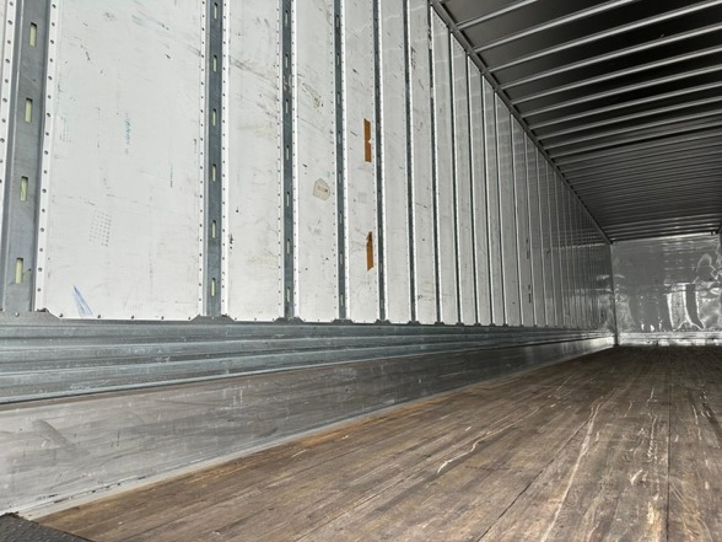 Trailer interior showing metal side walls with vertical stake pockets and wooden floor in a used 2023 Utility 4000dx trailer.
