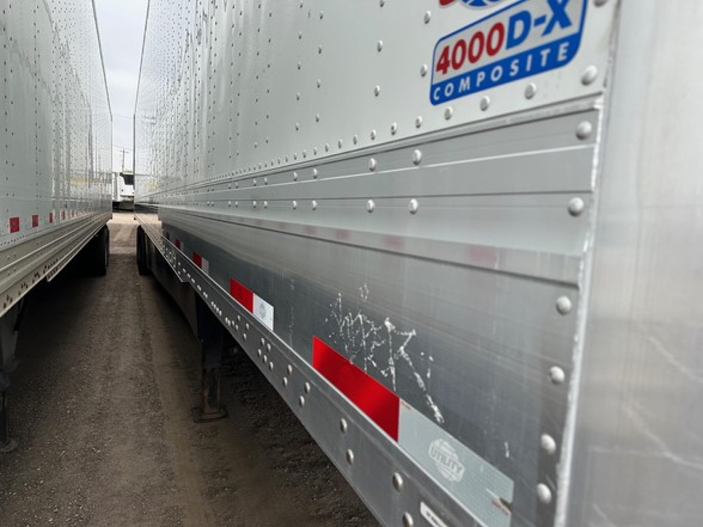 Trailer side showing 4000-D-X composite sticker on the upper front corner, riveted aluminum siding with red reflective strips.