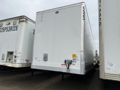 Utility 4000dx trailer front view with hitch and side door, white exterior, VIN-style markings, and adjacent trailers in lot.
