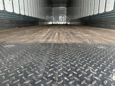 Trailer interior showing wood floor and diamond plate metal threshold with side rails and ceiling; empty cargo space.