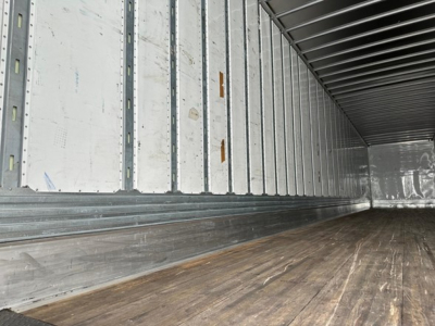 Trailer interior showing metal side walls with vertical stake pockets and wooden floor in a used 2023 Utility 4000dx trailer.