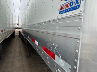 Trailer side showing 4000-D-X composite sticker on the upper front corner, riveted aluminum siding with red reflective strips.