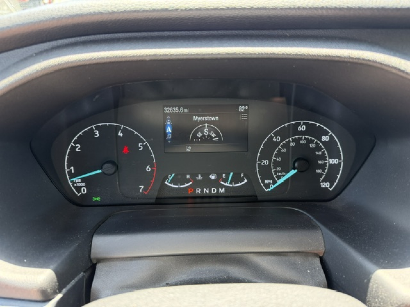 Dashboard view of a 2023 Ford Transit 350HD showing instrument cluster with speedometer, tachometer, central digital display, and gear selector PRNDM.