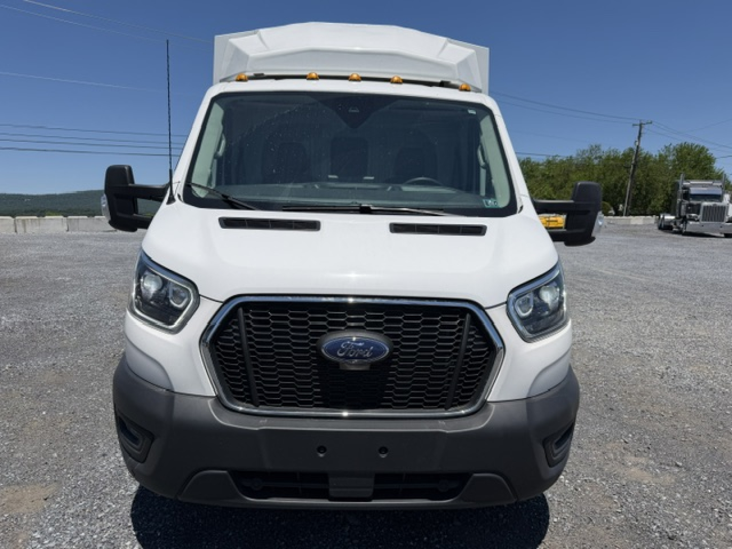 Ford Transit 350HD van front view showing grille and headlights with service body, daylight, gravel lot.