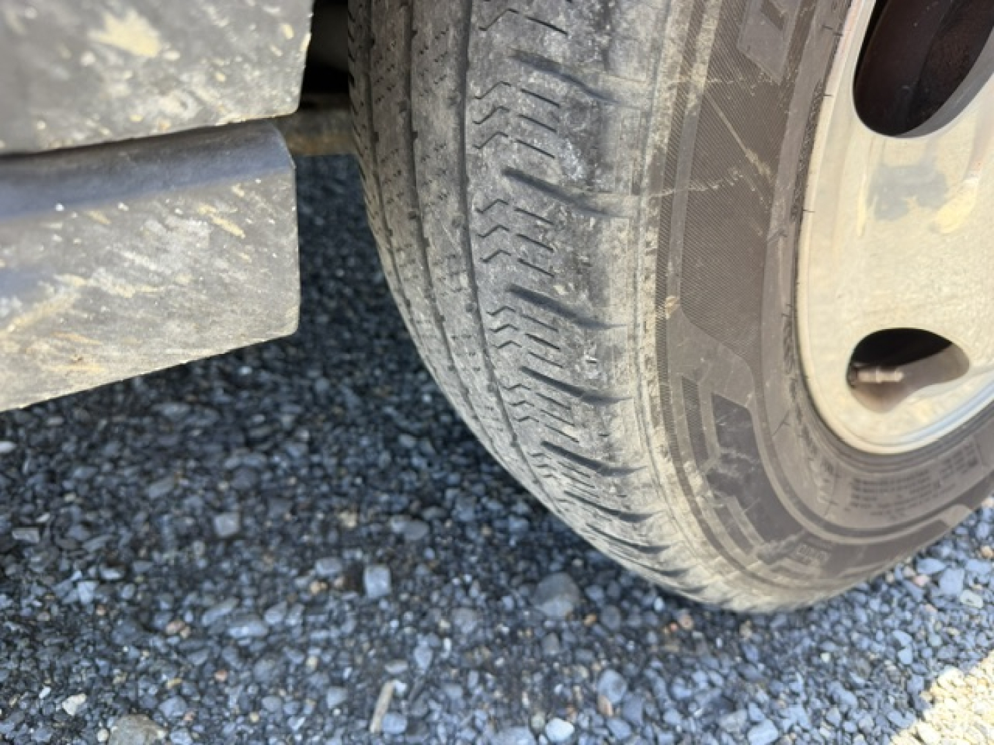 Ford Transit 350HD wheel and tire visible under the vehicle, mud and gravel underneath.