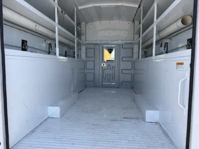 Ford Transit 350HD cargo van interior with empty cargo space and side wall racking, white molded panels, and rear doors open.