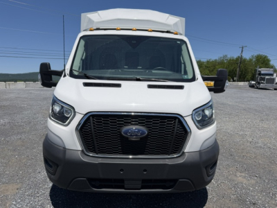Ford Transit 350HD van front view showing grille and headlights with service body, daylight, gravel lot.