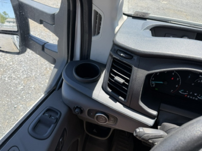 Ford Transit 350HD interior dash area with steering wheel, HVAC vent, cup holder, and control knob near door; partial instrument cluster visible
