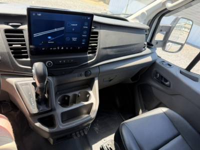 Ford Transit 350HD cabin interior showing dashboard with touchscreen display, gear selector, cup holders, and passenger seat.