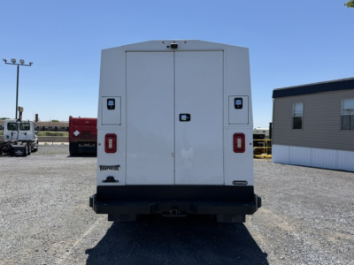 Ford Transit 350HD cargo van rear view showing double rear doors with black hinges and red taillights; service/utility truck in a gravel lot.