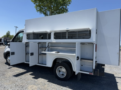 Ford Transit 350HD service utility truck side compartments open showing storage cabinets and work surface.
