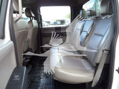 Ford F-550 cab interior with rear bench seats in light gray, 3-row seating visible, black rubber floor mats, window view through rear doors.