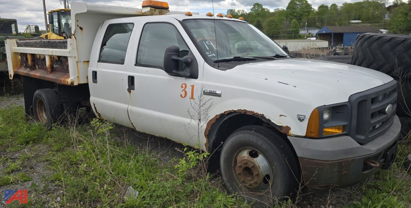 Ford F-350 Super Duty XL dump truck side view with rust along wheel arches and orange emergency beacon on cab roof.