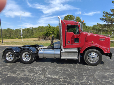 Kenworth T800 conventional daycab truck in red with chrome fuel tanks and dual rear axles.