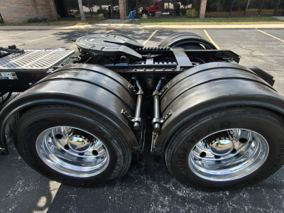 Dual rear tractor axles and fifth wheel on a Kenworth T800 cab chassis showing polished chrome wheels and heavy-duty tires.